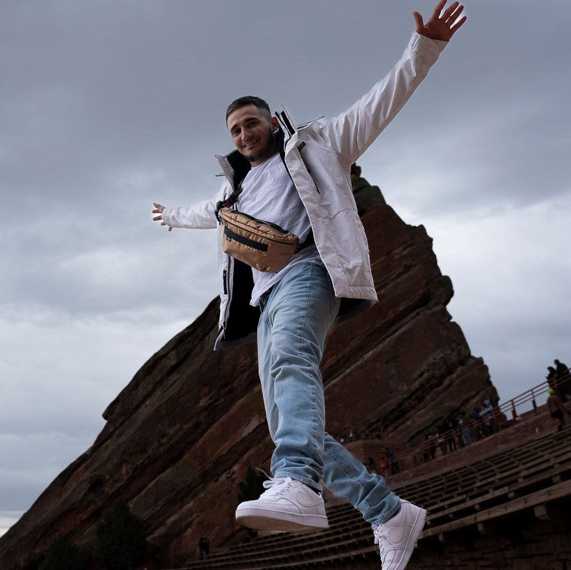 Man flying with ANDI fanny pack in cross-body style at Red Rocks | Metallic Rose Gold | Nylon