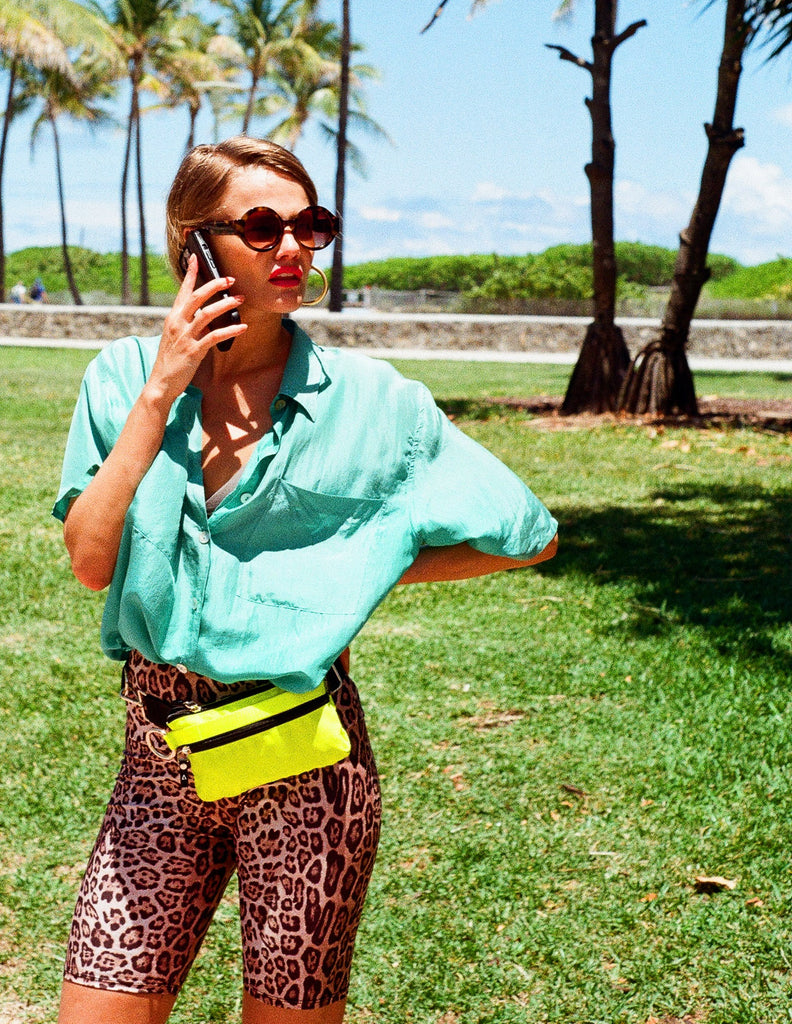 Woman wearing hot yellow ANDI convertible small purse as a belt bag